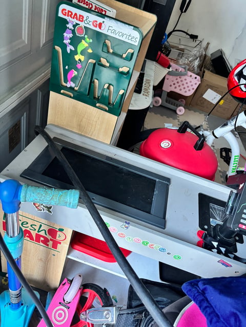 Cluttered desk workspace with computer monitor, Grab and Go Favorites organizer board, red headphones, and various toys and office supplies